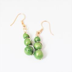 "These dangle bead earrings are made from layers and swirls of lime green polymer clay with shimmers of gold leaf. The earrings are three beads with gold tone wire work and French hooks with silicone safety backs.  Sizes are approx. 1\" long  (from where it attaches at the French wire) and 1 7/8\" long from the top of the wire, and the largest beads are approx. 3/8\" wide at the largest bead. Gold tone findings and wire work. French hooks also have a silicone safety backs These were handmade by me. Very lightweight and easy to wear. They have been sanded and buffed to a nice sheen. Polymer clay is tough but flexible. They should not be worn in the water though. I do my best to capture the colors when I photograph my jewelry, but please know that monitors can alter the colors." Dangle Bead Earrings, French Wire, Wire Work, Gold Wire, Etsy Earrings Dangle, Bead Earrings, Beaded Dangles, Green Bead, Gold Leaf