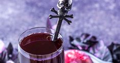 a glass filled with liquid and a skull on the top is sitting in front of some halloween decorations