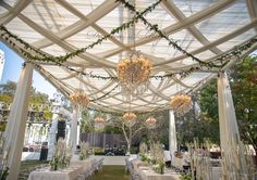 an outdoor wedding setup with chandeliers and tables