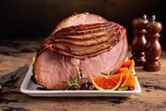 a large piece of meat sitting on top of a white plate next to sliced oranges