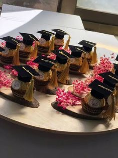 there are many graduation hats and tassels on the tray with flowers in front of them