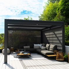 an outdoor living area with couches, tables and plants on the decking floor