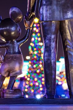 a statue of a man holding the hand of a little boy in front of a christmas tree