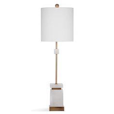 a white and gold lamp with a white shade on the top, sitting on a wooden base