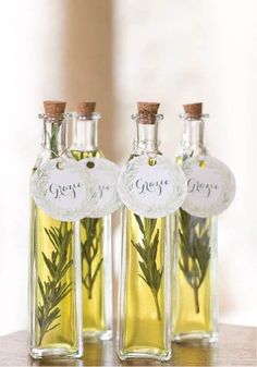 three small bottles filled with olive oil and rosemary sprigs sitting on a table