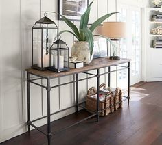 a table with some plants on top of it and a lamp in the corner next to it