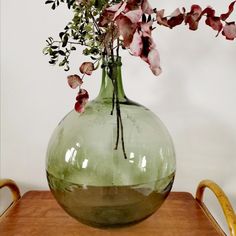 a green vase filled with flowers on top of a wooden table