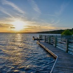 the sun is setting over the water and there are wooden docks in front of it