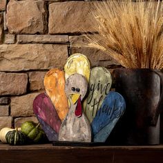 a wooden turkey sitting on top of a table next to a potted plant and some gourds