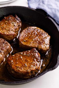 some steaks are cooking in a skillet