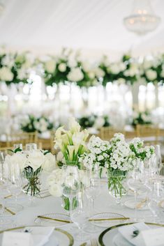 the table is set with white flowers and gold rimmed glasses for centerpieces