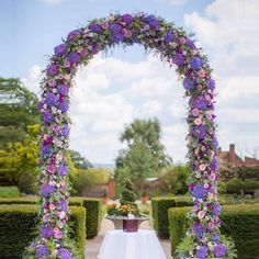 an archway decorated with purple flowers and greenery for a formal wedding or reception venue