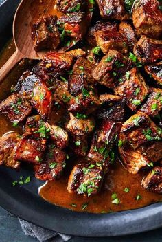 a pan filled with meat covered in sauce and garnished with fresh parsley