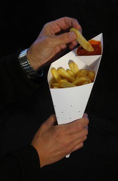 a person holding a paper container filled with fries