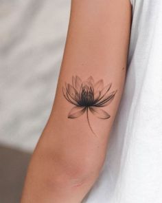 a woman's arm with a black and white flower tattoo on her left arm