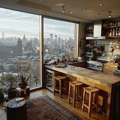 a kitchen with an island and bar stools in front of large windows overlooking the city