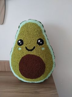 a stuffed avocado pillow sitting on top of a wooden table