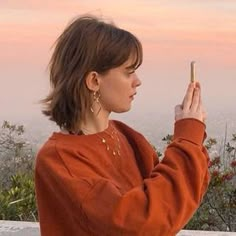 a woman is looking at her cell phone while standing in front of the hollywood sign