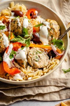 a bowl filled with pasta and meatballs on top of a table next to bread