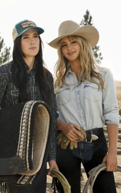 two women standing next to each other wearing cowboy hats