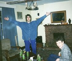 two men sitting on the floor in front of a fire place with their arms outstretched