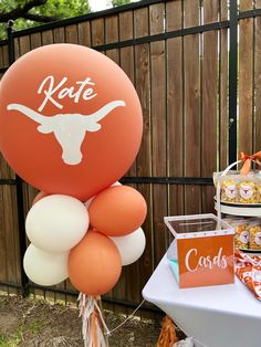 an orange and white balloon with the word kate on it sitting in front of a table