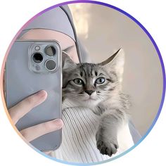 a person holding a cell phone up to their face with a cat on it's back