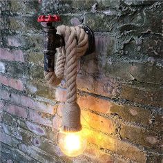 a light that is on the side of a brick wall with a rope hanging from it