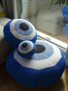 two blue and white pillows sitting on top of a wooden floor next to a window