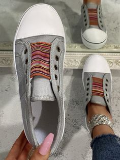 a woman's foot wearing white shoes with colorful stripes on the side and pink toenails