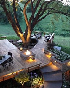 an outdoor deck with fire pit and seating area at dusk, lit up by lights