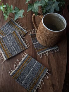 a wooden table topped with two mugs and rugs