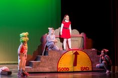 children on stage dressed as characters from the show good luck and bad times with an adult