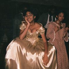 a woman in a gold dress sitting next to another woman