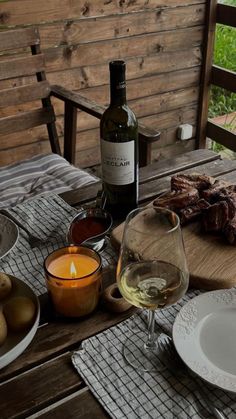 an outdoor table with food and wine on it