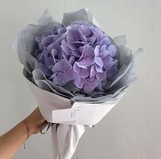 a person holding a bouquet of purple flowers