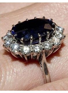 a woman's hand with an oval shaped blue sapphire and diamond ring on it