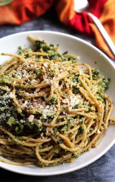 a white bowl filled with pasta and broccoli covered in parmesan cheese