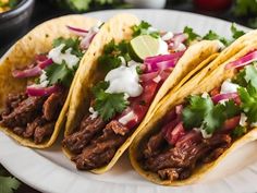 three tacos with meat, onions and cilantro on a plate