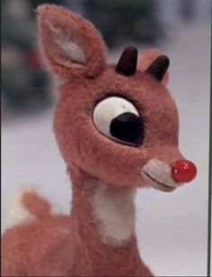 a close up of a stuffed animal deer with big eyes and red nose on it's head