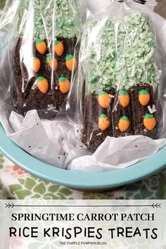 two brownies with green frosting and carrots on them in plastic wrappers