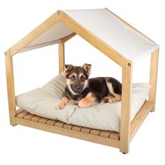 a small dog laying on top of a pillow in a wooden house shaped like a bed