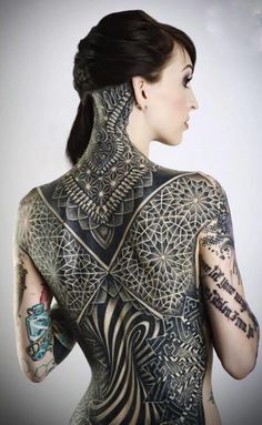 a woman with lots of tattoos on her back and arms, standing in front of a black and white background