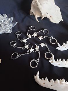 several pieces of silver and white jewelry on a black surface with an animal's teeth