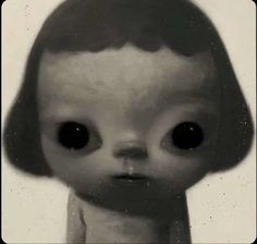 an old black and white photo of a weird looking doll with big eyes on it's head