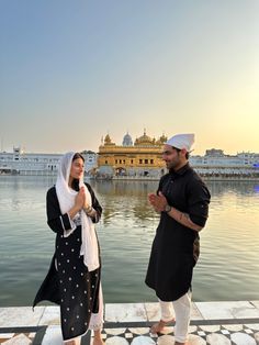 two people standing on the edge of a body of water