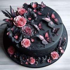 a black cake with pink flowers and butterflies on it