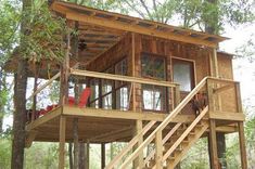 a tree house built in the woods with stairs leading up to it's second floor