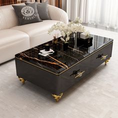 a black and gold coffee table with flowers on it in front of a white couch