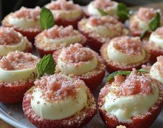 several strawberry cupcakes with powdered sugar and mint leaves on top, sitting on a white plate